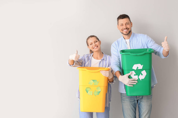 Couple with containers for garbage showing thumb-up on white background. Concept of recycling - Foto, immagini