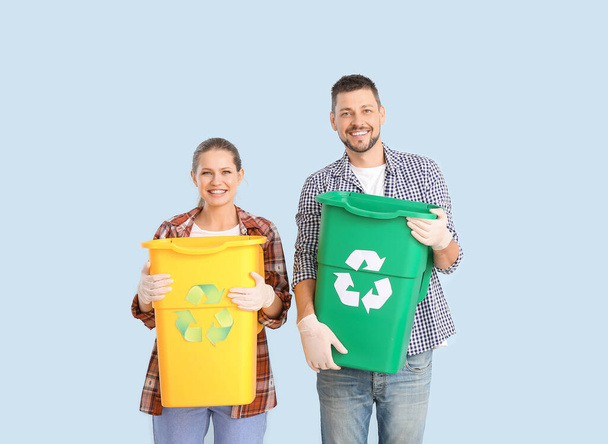 Paar mit Behältern für Müll auf farbigem Hintergrund. Recyclingkonzept - Foto, Bild