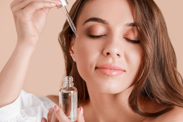 Beautiful young woman applying serum onto her skin against light background, closeup - Foto, Bild