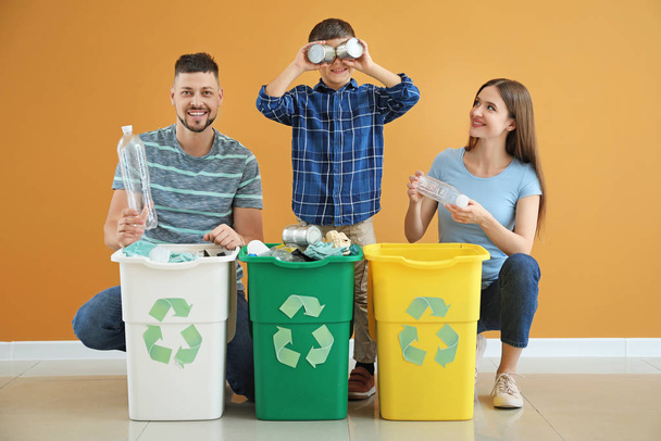 Счастливая семья с контейнерами для мусора на цветном фоне. Концепция переработки
 - Фото, изображение