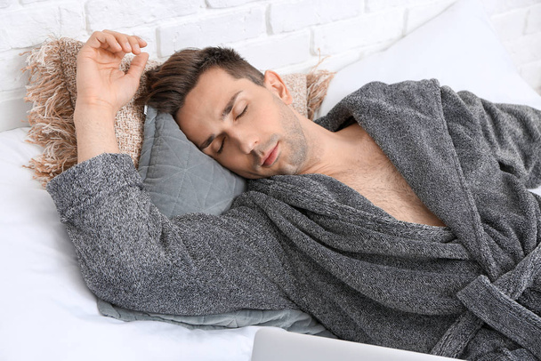 Beau homme en peignoir dormant sur le lit
 - Photo, image