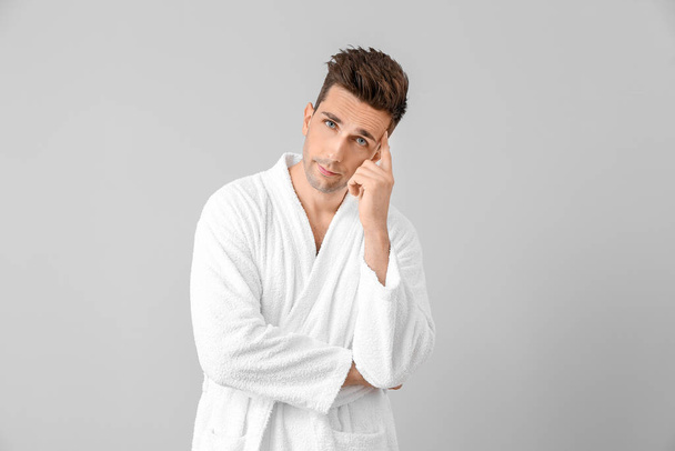 Handsome man in bathrobe on grey background - Photo, Image