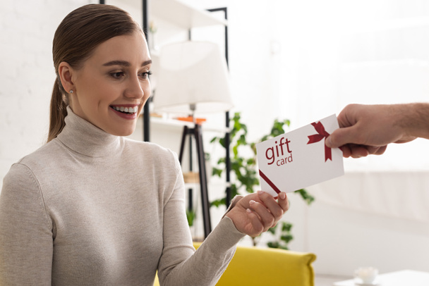Man giving gift card to beautiful smiling woman at home - Fotografie, Obrázek