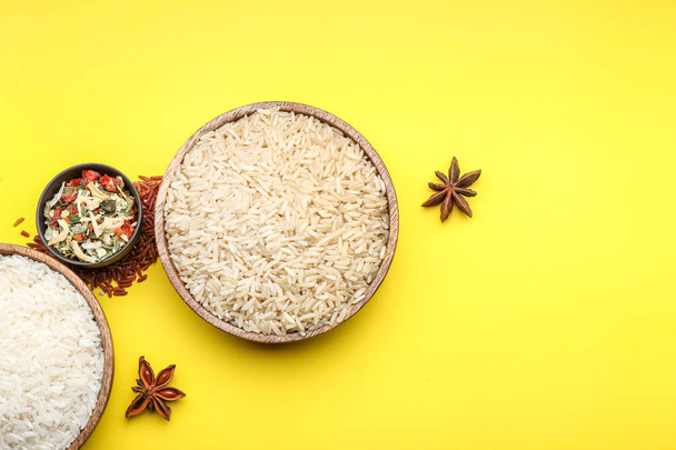 Тарелки с сырым рисом, овощами и специями на цветном фоне
 - Фото, изображение