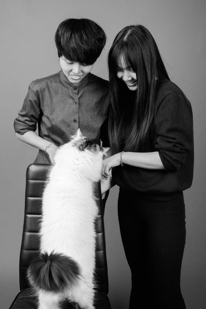 Studio shot młodej azjatyckiej pary lesbijek razem i w miłości na szarym tle w czerni i bieli - Zdjęcie, obraz