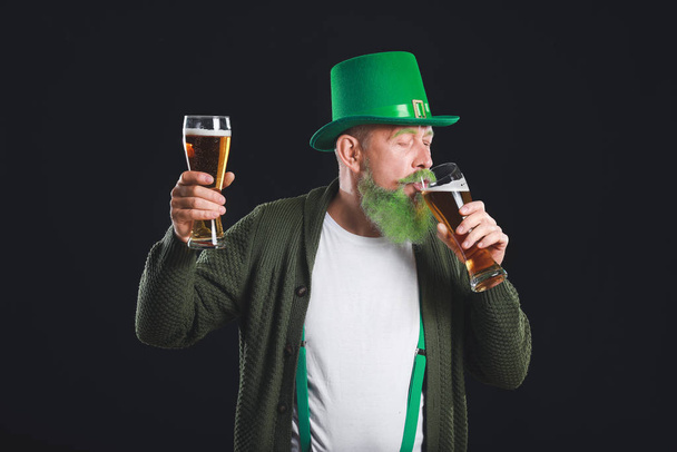 Αστείος ώριμος άντρας με ποτήρια μπύρας σε σκούρο φόντο. Γιορτή του Αγίου Πατρικίου - Φωτογραφία, εικόνα