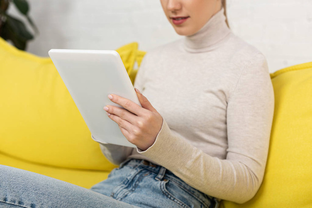Cropped view of young woman using digital tablet on couch - Valokuva, kuva