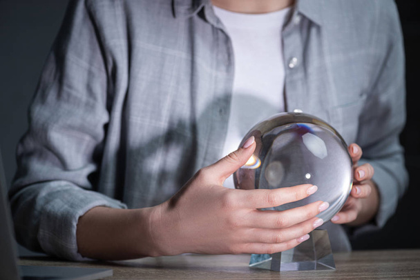 Cropped view of woman using crystal ball on wooden table - Foto, afbeelding