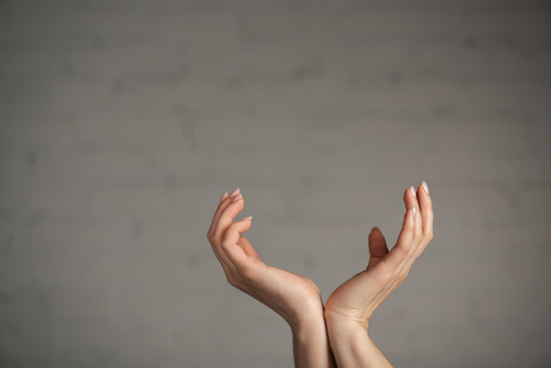 Oříznutý pohled na ženu gestikulující rukama na šedém pozadí - Fotografie, Obrázek