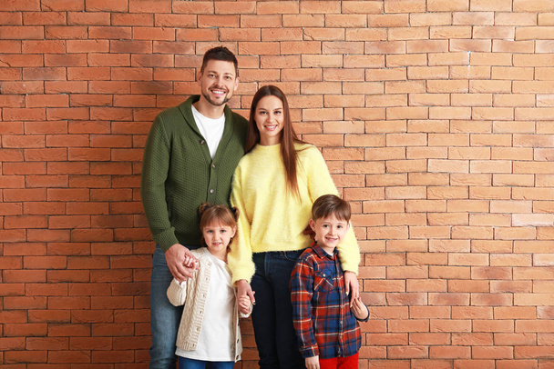 Família feliz em roupas de inverno perto da parede de tijolo
 - Foto, Imagem
