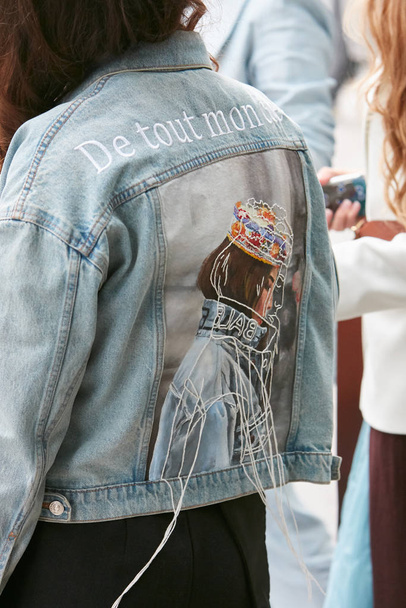 Woman with blue denim jacket and woman design on back before Emporio Armani fashion show, Milan Fashion Week street style  - 写真・画像