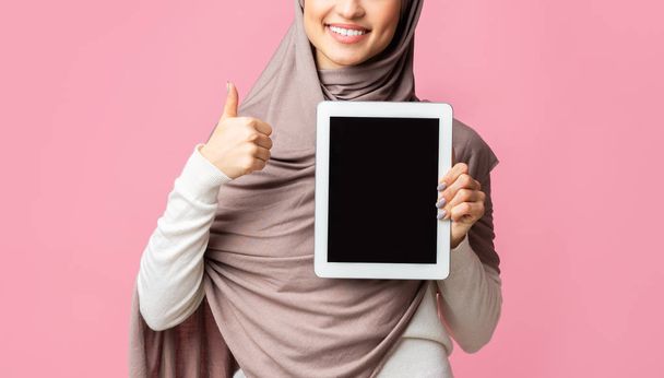 Muslimisches Mädchen mit Kopftuch demonstriert digitales Tablet mit schwarzem Bildschirm - Foto, Bild