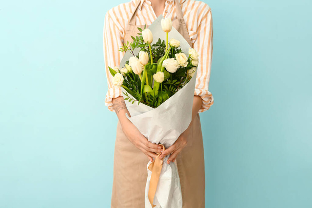 Female florist with beautiful bouquet on color background - 写真・画像