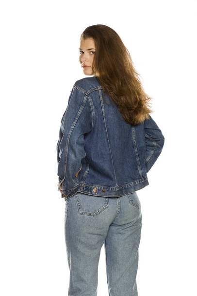 Back view of young woman in jeans jacket on white background - Foto, imagen