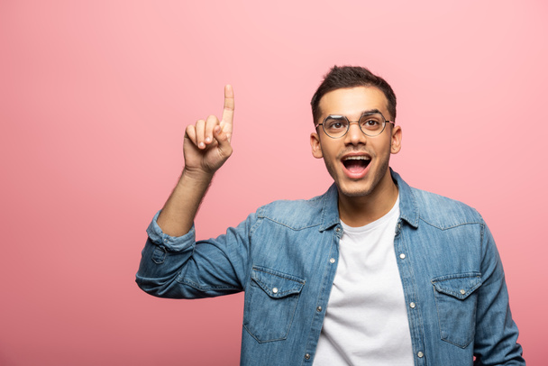 Young excited man pointing with finger and looking away isolated on pink - Foto, Imagen