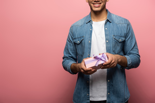 Cropped view of smiling man holding gift box on pink background - Фото, изображение