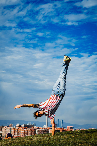 B-boy εκτελεί κάποιες κινήσεις. Breakdancer στη σύγχρονη πόλη φόντο - Φωτογραφία, εικόνα