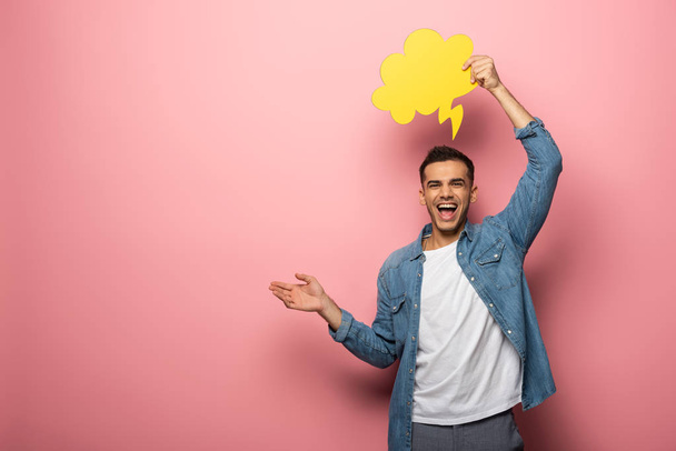 Cheerful man with speech bubble pointing with hand on pink background - Fotó, kép