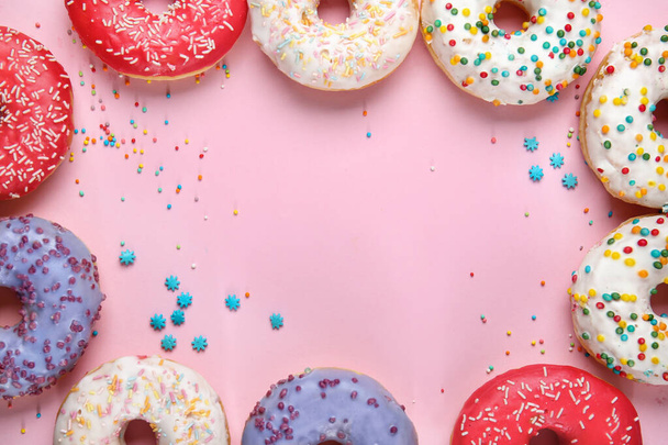 Frame made of sweet tasty donuts on color background - 写真・画像