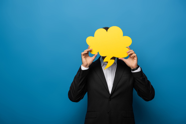 Businessman covering face with speech bubble on blue background - Foto, Bild