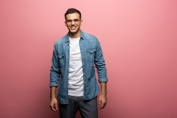 Handsome young man smiling at camera on pink background - 写真・画像