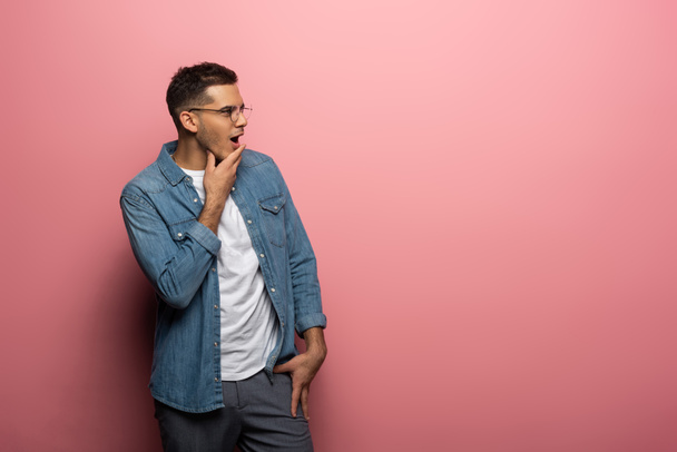Side view of shocked man looking away on pink background with copy space - Фото, изображение