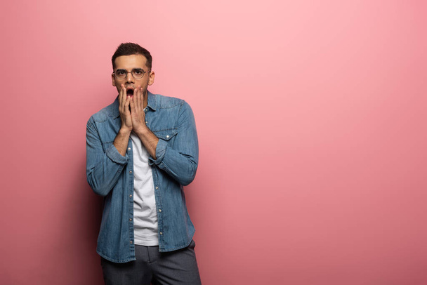 Shocked man with hands by face looking at camera on pink background - Photo, Image