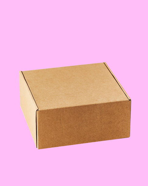 Kraft cardboard square closed box top view. The box is carved on a pink background. - Fotografie, Obrázek