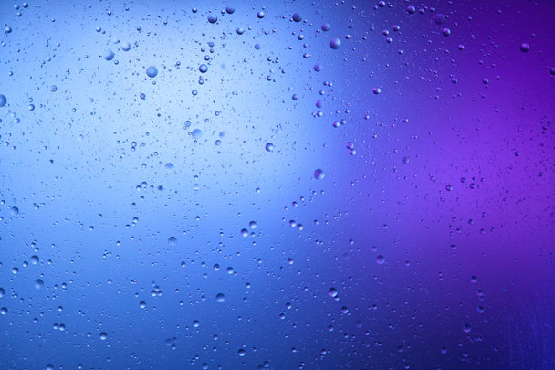 schöner abstrakter Hintergrund aus gemischtem Wasser und Öl in blauer und lila Farbe - Foto, Bild