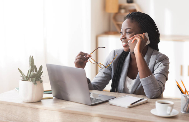 Успішна чорна бізнес-леді розмовляє на мобільному телефоні на робочому місці в офісі
 - Фото, зображення
