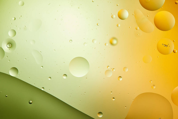 abstract creative background from mixed water and oil in green and orange color - Foto, afbeelding
