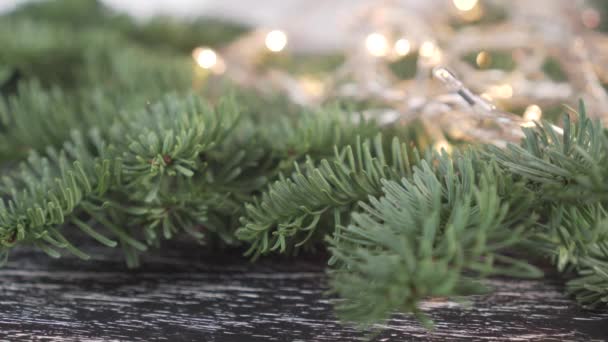 The dense branches of a live spruce with beautiful green needles on the background of a blinking Christmas garland with yellow lights with bokeh. Festive mood awaiting Christmas - Footage, Video
