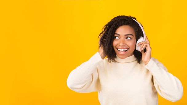 lächelndes Afro-Mädchen, das Musik mit Kopfhörern genießt - Foto, Bild