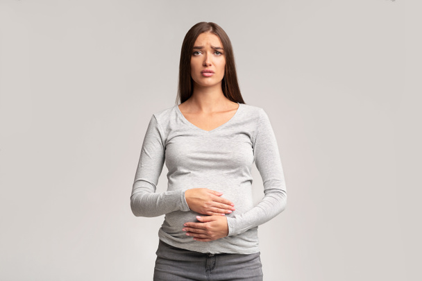 Грустная беременная женщина, прикосновение живота стоя, студия выстрел
 - Фото, изображение