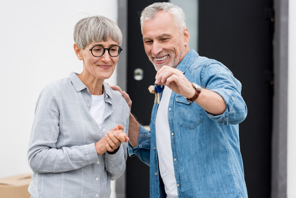 mature man holding keys of new house and smiling woman looking at it  - 写真・画像