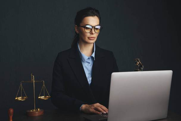 Lawyer office. Statue of Justice with scales and lawyer working on a laptop. Legal law, advice and justice concept - Photo, image