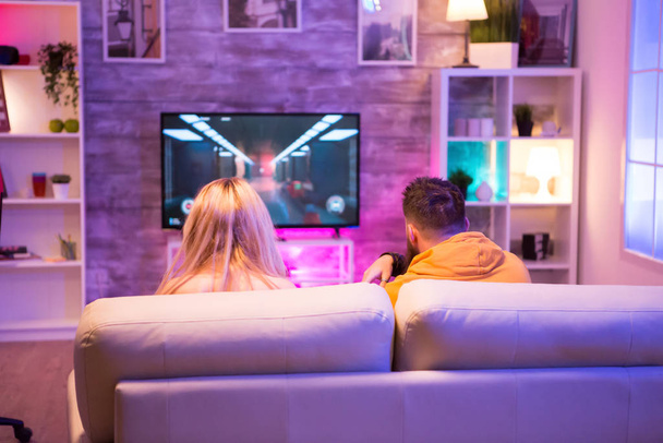 Back view of friends playing shooter games sitting on sofa - Foto, Bild