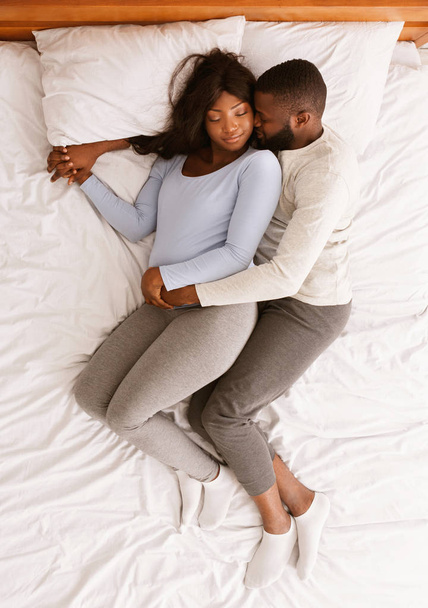 Μαύρο προσδοκώμενο ζευγάρι που κοιμάται στο κρεβάτι, πάνω όψη - Φωτογραφία, εικόνα