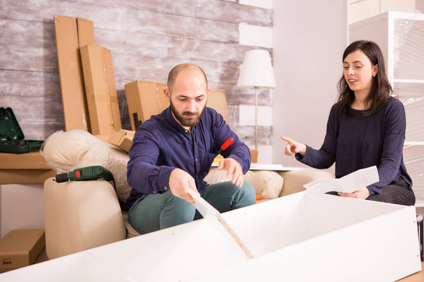 Vriendje monteert meubels in hun nieuwe appartement - Foto, afbeelding
