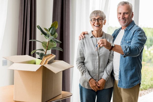 smiling man holding keys of new house and hugging woman  - Photo, Image