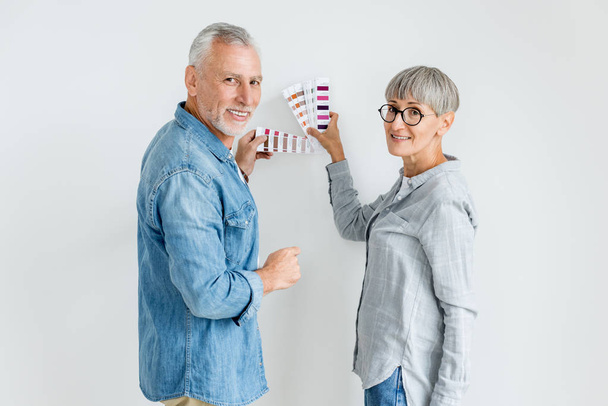 volwassen man en vrouw met palet kijken naar camera in nieuw huis  - Foto, afbeelding
