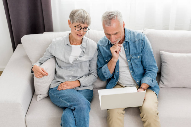зрелый мужчина и женщина, глядя на ноутбук в новом доме
  - Фото, изображение