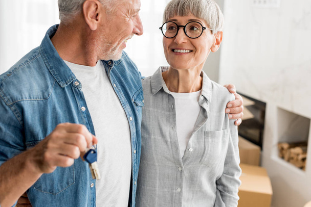 cropped view of smiling man holding keys and looking at woman in new house  - Photo, Image