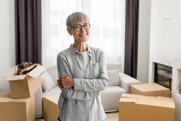 smiling woman with crossed arms looking at camera in new house  - Photo, Image