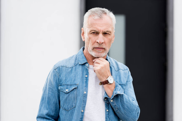 pensive mature man in shirt looking away near new house  - Foto, Imagem