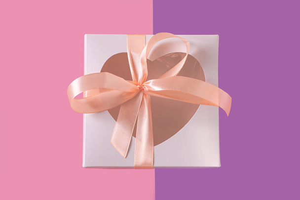 Caixa de presente branco com janela em forma de coração e etiqueta de cartão no fundo púrpura pastel flatlay, conceito mínimo criativo
. - Foto, Imagem