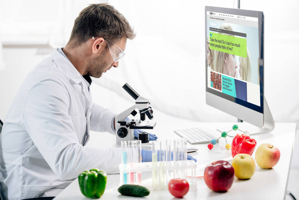 KYIV, UKRAINE - OCTOBER 4, 2019: side view of molecular nutritionist using computer with bbc website  - Foto, immagini