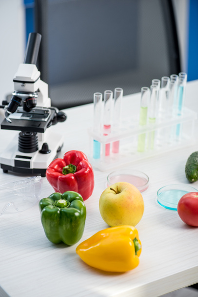 microscoop, fruit, groenten, reageerbuizen op tafel in het lab  - Foto, afbeelding