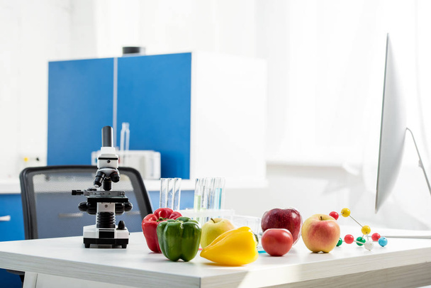 Laboratuvardaki masada mikroskop, meyve, sebze ve tüpler var.  - Fotoğraf, Görsel