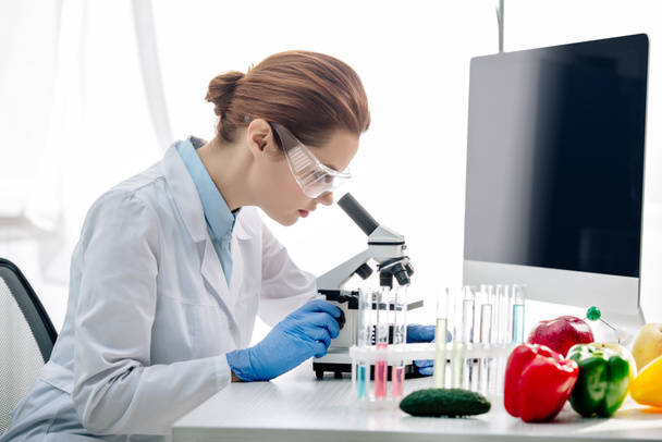 side view of molecular nutritionist using microscope and sitting at table  - Foto, Imagem